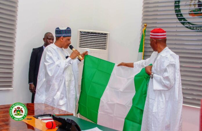 HE Governor Abba Kabir Yusuf's of Kano State presenting the National Flag to the Hon. Minister of Information and National Orientation, Alhaji Mohammed Idris Malagi