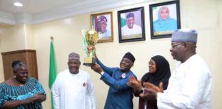 The Honourable Minister of Education Dr Maruf Tunji Alausa raising the trophy and flaked by the Permanent Secretary Dr Nasir Sani-Gwarzo with Directors