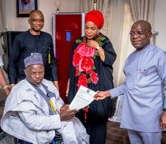 L-R: Executive Secretary NCPWD, Hon. Ayuba Gufwan presenting an appreciation letter to Governor Alex Otti (R) while Her Excellency Mrs Priscillia Otti (M) and Mr David Anyaele, Chairman Commission for the Welfare of the Disabled Persons (behind) looks on