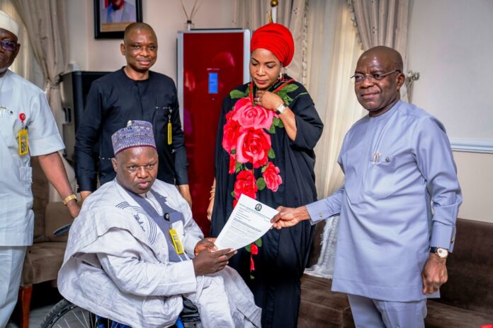 L-R: Executive Secretary NCPWD, Hon. Ayuba Gufwan presenting an appreciation letter to Governor Alex Otti (R) while Her Excellency Mrs Priscillia Otti (M) and Mr David Anyaele, Chairman Commission for the Welfare of the Disabled Persons (behind) looks on