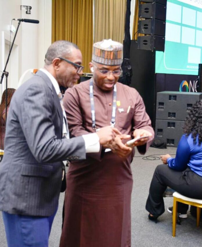 The Permanent Secretary MPR. Dr. Emeka Vitalis Obi mni (right) tutoring a visitor to the MPR's Exhibition Booth about the operationalisation of the Ministry's Scan Code at the 2025 NOG Energy Week in Abuja.