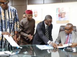 Honourable Minister of State for Health & Social Welfare Dr. Iziaq Adekunle Salako signing on behalf of the Ministry. Wearing red cap: Founder & Pro- Chancellor Achievers University Owo, Prof. Bode Ayorinde; 1st Left Dr. Hamed Liasu Medical Director Federal Medical Centre Owo- Ondo State. Wearing suite: The Director Legal Services Department of the FMoHSW, Barrister Okohagiam