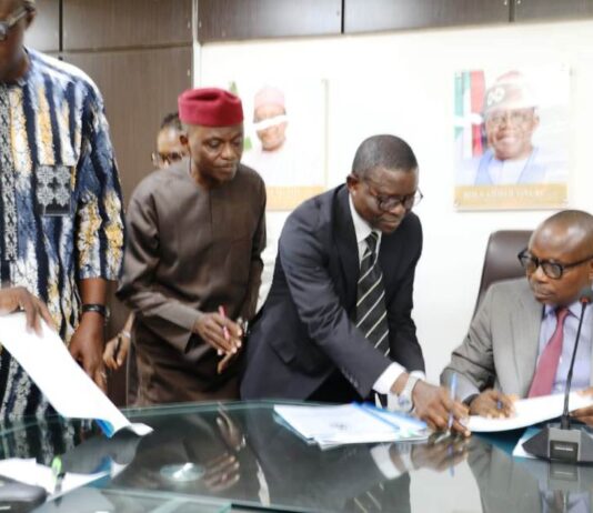 Honourable Minister of State for Health & Social Welfare Dr. Iziaq Adekunle Salako signing on behalf of the Ministry. Wearing red cap: Founder & Pro- Chancellor Achievers University Owo, Prof. Bode Ayorinde; 1st Left Dr. Hamed Liasu Medical Director Federal Medical Centre Owo- Ondo State. Wearing suite: The Director Legal Services Department of the FMoHSW, Barrister Okohagiam