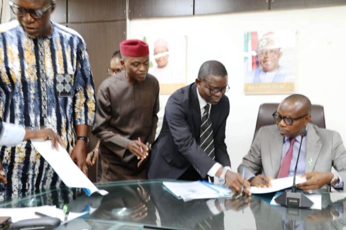 Honourable Minister of State for Health & Social Welfare Dr. Iziaq Adekunle Salako signing on behalf of the Ministry. Wearing red cap: Founder & Pro- Chancellor Achievers University Owo, Prof. Bode Ayorinde; 1st Left Dr. Hamed Liasu Medical Director Federal Medical Centre Owo- Ondo State. Wearing suite: The Director Legal Services Department of the FMoHSW, Barrister Okohagiam