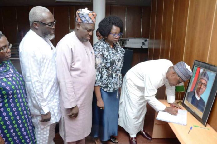 The Permanent Secretary, Ministry of Regional Development, Dr. Mary Ada Ogbe with top management staff look on as, the Honourable Minister, Ministry of Regional Development, Engr. Abubakar Momoh signing the Condolence Register of late former President Muhammadu Buhari, in his office on the 11th floors, Federal Secretariat Phase 1, Abuja.