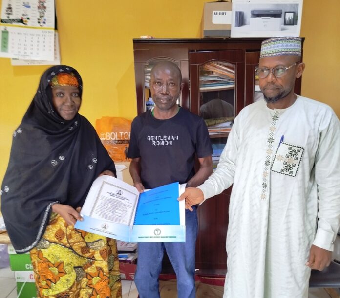Mrs. Jimeta The Acting Executive Director, Nigeria Integrated Water Resources Management Commission (NIWRMC), Mrs. Sakinatu Suleiman Abbo Jimeta (L) making presentation of the Water Use Licence to Engr Leo Morga, Technical Manager, Nigeria Mills, Calabar, (M) flanked by the Director, Allocation and Authorisation, Engr Shazali Uba Ajingi (R) in Abuja.