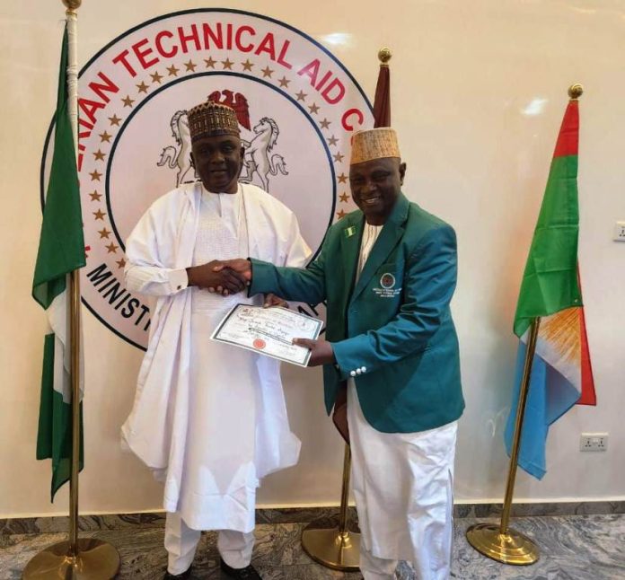 The DG/CEO NTAC pictured presenting the Returnee Volunteer, Prof. Joseph Tanko Apagu (in NTAC Blazers) with the Certificate of Completion