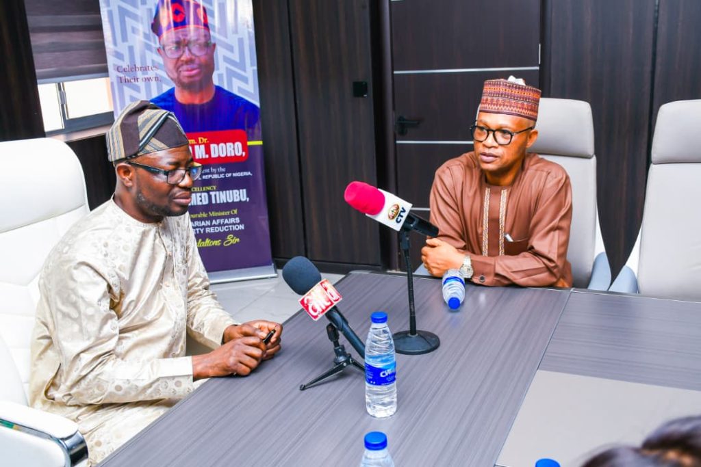 The honourable minister of Humanitarian Affairs and Poverty Reduction. Dr. Bernard M. Doro responded to the quest when the Arch Bishop of Abuja paid him a courtesy visit in his office.  
Besides him is the permanent secretary in the ministry. Mr Olubunmi Olusanya.