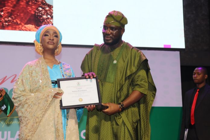 IMG-20260515-WA0094 The Honourable Minister of Federal Ministry of Art, Culture Tourism and Creative Economy, Barr Musa Musawa receiving her certificate by the Director General/ Chief Executive Officer of NIHOTOUR during the induction and certification ceremony recently at Merit House, Abuja.