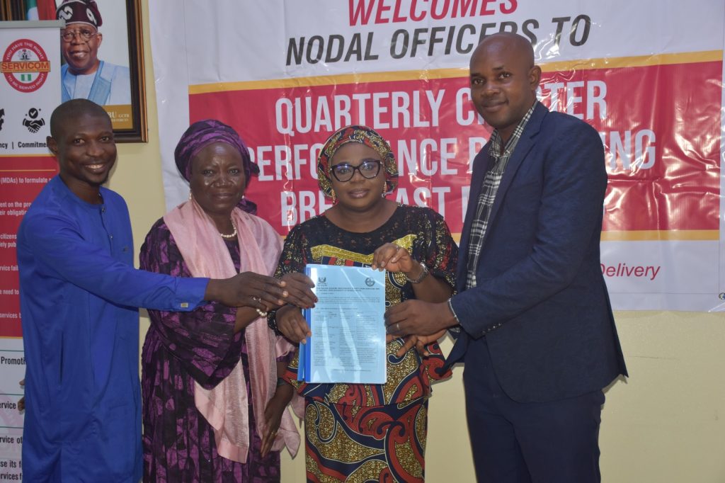 R-L : NOUN SERVICOM Desk Officer, Mr. Matthew Oguche (1st), NOUN Nodal Officer Mrs. Foluke Adeniran (3rd) and Mr. Idris Adama (4th) presenting a copy of their Charter Performance Report to the Ag. National Coordinator/CEO of SERVICOM Office, Mrs. Helen Lawal (2nd) during the meeting.