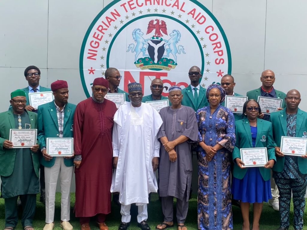 Director-General/Chief Executive Officer of the Nigerian Technical Aid Corps (NTAC), Rt. Hon. Yusuf Buba Yakub (centre), flanked by the Director of Programmes, Ambassador Bello A. Jaye (right); Resource Person, Ambassador Sani Bako (left); Deputy Director (Administration), Ambassador Gwendy O.; and the 11 Returning NTAC Volunteers from The Gambia during their Debriefing Session, held on Monday, 20th July, 2026, at the NTAC Complex, Abuja.