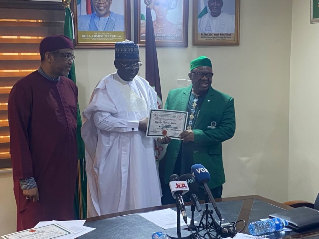 Director-General/Chief Executive Officer of the Nigerian Technical Aid Corps (NTAC), Rt. Hon. Yusuf Buba Yakub, presenting a Certificate of Service to the Team Lead of the Returning Volunteers, Engr. Oyetunji A. Akinlabi, as the Director of Programmes, Ambassador Bello A. Jaye, looks on during the Debriefing and Support Session for the Returning NTAC Volunteers from The Gambia, held on Monday, 20th July, 2026, at the NTAC Complex, Abuja.