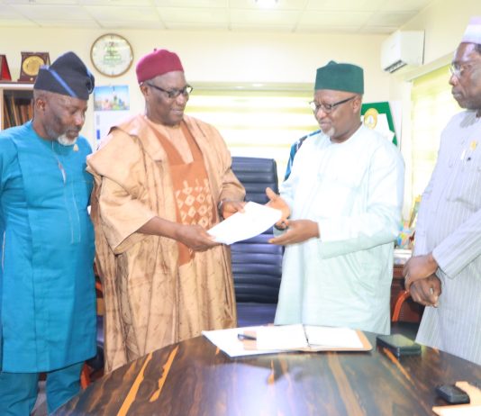 The Chairman of CORBON, Bldr. Samson Ameh Opaluwah (second left), presents a document to the President of COREN, Engr. Prof. Sadiq Zubair Abubakar, FNSE, FAEng, during the courtesy visit, as senior officials of both Councils look on.
