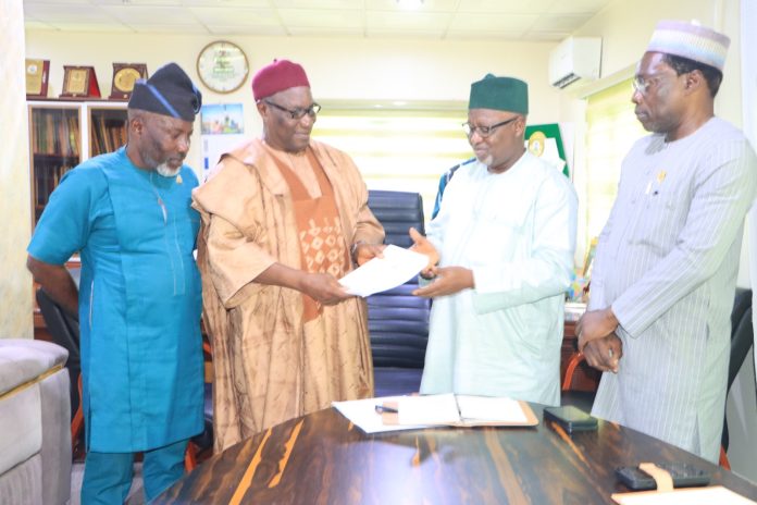 IMG-20260723-WA0120 The Chairman of CORBON, Bldr. Samson Ameh Opaluwah (second left), presents a document to the President of COREN, Engr. Prof. Sadiq Zubair Abubakar, FNSE, FAEng, during the courtesy visit, as senior officials of both Councils look on.