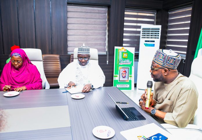 R:- The Honourable Minister of Humanitarian Affairs and Poverty Reduction. Dr. Bernard M Doro responds to the Registrar, Pharmacy Council of Nigeriaby his left in white, Pharmacist Ibrahim Baba Shehu Ahmed when the team from the council visited him in his office in Abuja.