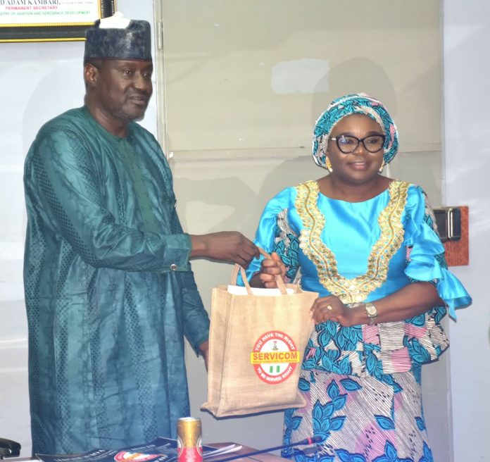 IMG-20260904-WA0000 The Ag. National Coordinator/CEO of the SERVICOM Office, Mrs. Helen Lawal presenting some awareness materials to the Permanent Secretary, Federal Ministry of Aviation and Aerospace Development, Mr. Mahmud Adam Kambari FCNA, FICA, during the courtesy visit to the Ministry’s Headquarters in Abuja on 3rd September, 2026.