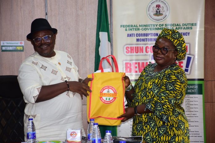 IMG-20261029-WA0083 SERVICOM Head of Operations, Mrs. Ngozi Akinbodewa, presenting some Awareness Materials to the Permanent Secretary, Federal Ministry of Special Duties and Intergovernmental Affairs, Dr. Onwusoro Maduka I., during the inauguration of the newly appointed Ministerial SERVICOM Committee (MSC) members and the Permanent Secretary’s decoration as SERVICOM Champion at the Ministry’s Headquarters in Abuja on 29th October, 2026.